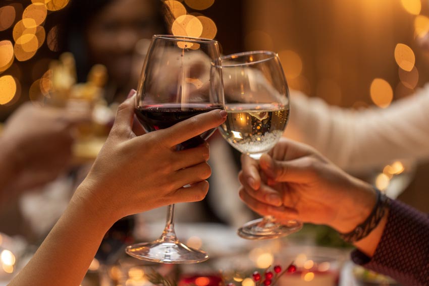 Zwei Hände mit jweils einem Glas Wein in der Hand stoßen an